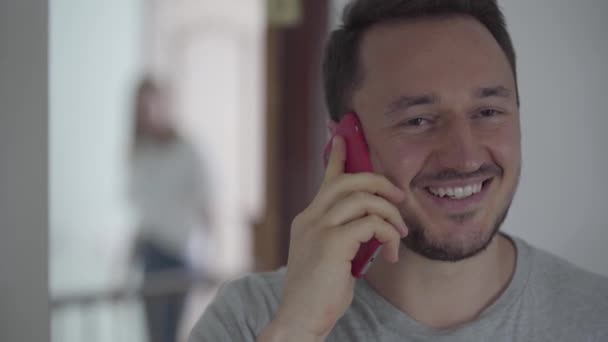 Portrait of happy man talking with his paramour by cellphone while his wife appears behind and overhearing the conversation. Family problems. Betrayal, mistrust, breakup concept. Focus on the man. — Stock Video