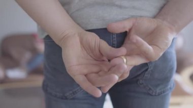 Tanınmaz bir adam bir parmağından altın bir düğün yüzüğü kaldırarak ve cebine koyar. İhanet, güvensizlik, ayrılık konsepti. Aile içinde yanlış anlama.