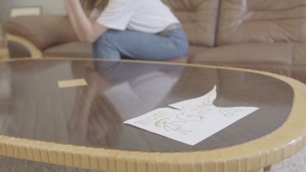 Unrecognizable crying woman on the background of torn childrens drawing with the image of mom and dad lying on the table. Betrayal, mistrust, breakup concept — Stock Video