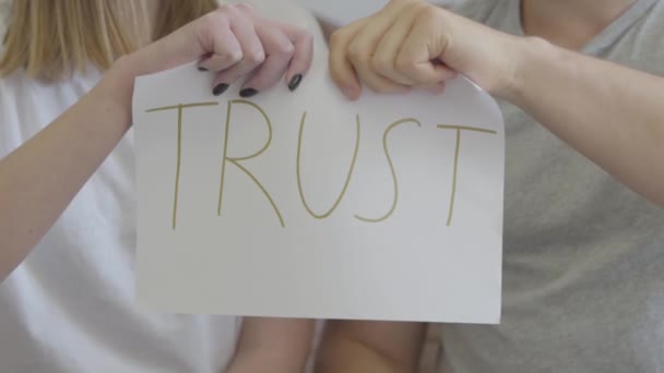 Händerna på man och kvinna Riva isär ordet Trust skrivet på papperet. Problem i relationen mellan man och kvinna. Svek, misstro, upplösning Concept — Stockvideo