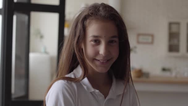 Retrato de una linda niña mirando a la cámara sonriendo felizmente y mostrando sorpresa en su cara en casa. Una infancia sin preocupaciones. Pequeña chica emocional adentro. Serie de personas reales . — Vídeo de stock