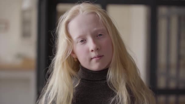 Portréja egy albínó lány szürke szeme nézte a kamerát mosolyogva. Szokatlan megjelenés. Gondtalan gyermekkor. Arca egy szőke kaukázusi lány hosszú haja. Valódi emberek sorozata. — Stock videók