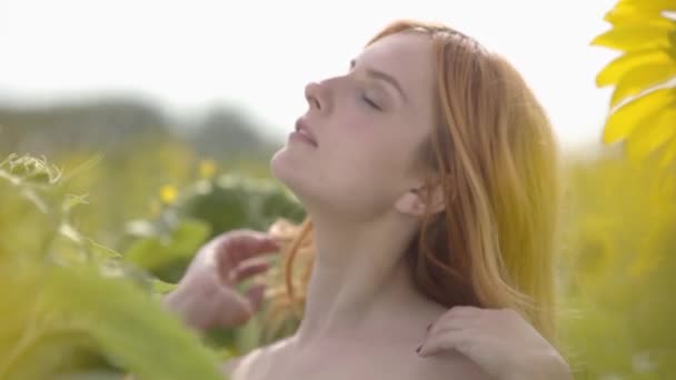Portret van schattige zelfverzekerde sensuele meid met rood haar en groene ogen staande op zonnebloem veld. Concept van schoonheid, verbinding met de natuur. Freedom concept. Gelukkige vrouw buitenshuis. — Stockvideo