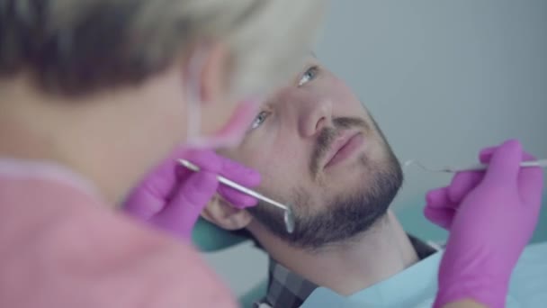 Tandarts in medisch masker en handschoenen controleren van de mond van de patiënt met behulp van medische hulpmiddelen. Vrouwelijke professionele arts hij op het werk. Tandheelkundige behandeling, medisch concept. Tandheelkundige verzorging. — Stockvideo