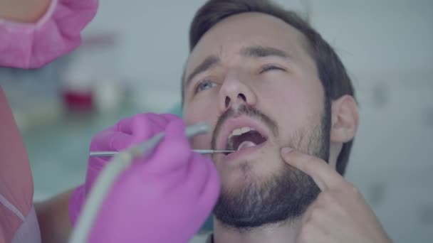 Dentiste en masque médical et gants vérifiant les dents du patient à l'aide d'outils médicaux. Médecin stomatologue professionnelle au travail. Traitement dentaire, concept médical. Soins dentaires . — Video