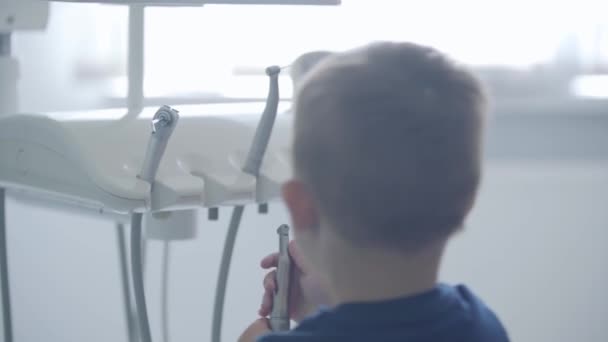 Joli petit garçon dans le cabinet de dentiste jouant tenant des outils médicaux. Enfant insouciant médecin visiteur. Traitement dentaire, concept médical. Soins dentaires . — Video