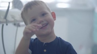 Dişçi ofisinde tıbbi aletlerle oynayan sevimli küçük çocuk. Tasasız çocuk misafir doktor. Diş tedavisi, tıbbi konsept. Diş bakımı.