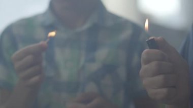 Karanlık dumanlı odada ateşle oynayan tanınmayan iki küçük kardeş. Bir çocuk arka planda çakmak yaktı başka ön planda bir kibrit yaktı. Çocuklar ateşle oynar. Kundakçılar