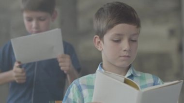 Dumanlı odada iki küçük ikiz kardeş. Bir çocuk arka planda bir çakmak ile kağıt yaktı başka bir çocuk ön planda okurken. Küçük kundaklama