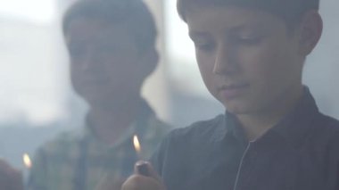 Karanlık dumanlı odada ateşle oynayan iki küçük kardeş. Bir çocuk arka planda çakmak yaktı başka ön planda bir kibrit yaktı. Çocuklar ateşle oynar. Kundakçılar