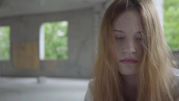 Portrait of caucasian young sad girl sitting in an abandoned building having drug breaking or waiting for support and help. — Stock Video