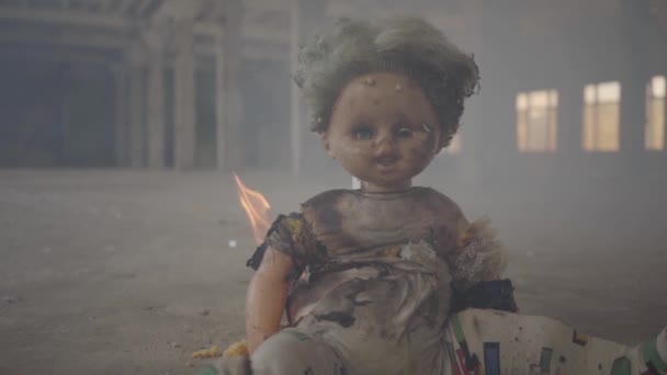 Scary doll burning on the floor in an abandoned smoky building. Concept of fire, flammability, non-compliance with safety rules. — Stock Video