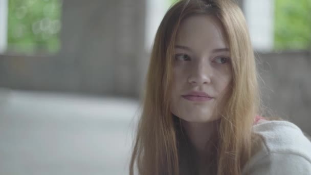 Retrato de chica triste con el pelo largo y rojo en una gran habitación vacía polvorienta en el edificio abandonado sintiéndose mal . — Vídeos de Stock