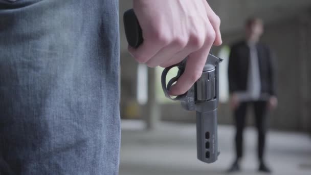Close-up van de mannelijke hand vasthouden van de revolver in de hand. De man plaatst en verwijdert vinger van de trigger. Een nerveuze jongeman die een mens gaat doden in een verlaten gebouw — Stockvideo