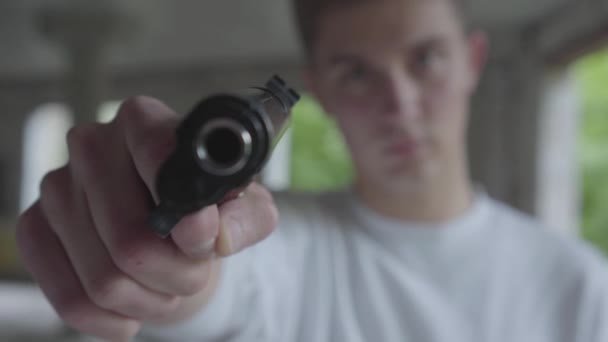 Young man aiming with the pistol, his hands shaking close-up. The guy is going to kill the human in an abandoned building — Stock Video