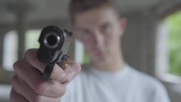 Jonge gedeconcentreerde man gericht met het pistool, zijn handen schudden close-up. De man gaat de mens doden in een verlaten gebouw — Stockvideo