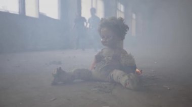 İki ikiz çocuk arka planda duman bulutu içinde karanlık oda ile çalışan. Ön planda yerde yanan korkunç bir bebek. Yangın kavramı, yanıcılık, güvenlik kurallarına uyulmaması.