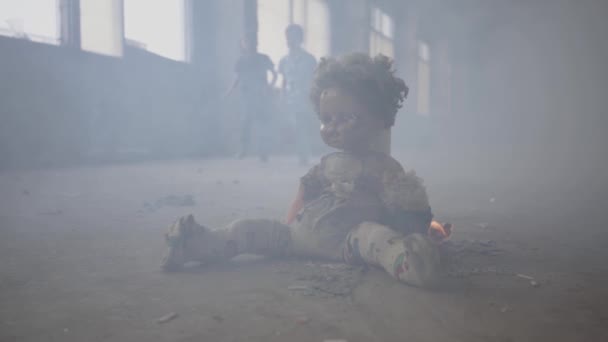 两个双胞胎男孩在背景的烟雾中穿过黑暗的房间。可怕的娃娃在前景的地板上燃烧。防火、易燃、不遵守安全规则的概念. — 图库视频影像