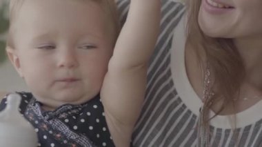 Yakın çekim güzel bir kız bebek mutfakta yardım ile küçük bebek şişesinden su içme. Mutlu bir aile, bir çocuk, annelik, aşk kavramı. Yavaş çekim