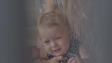 Annelerin kollarında oturarak ağlayan güzel bir kız bebek yakın çekim. Yaramaz çocuğunu beslemeye çalışan bir kadın. Annelik kavramı, büyüyen çocuklarda zorluklar, aşk. Yavaş çekim