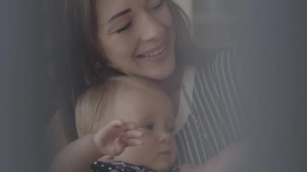Närbild av en vacker baby flicka dricksvatten från den lilla nappflaska med mödrar hjälp i köket. Begreppet en lycklig familj, ett barn, moderskap, kärlek. Slow motion — Stockvideo