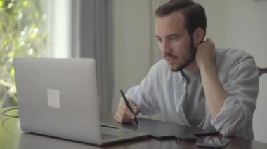 Başarılı sakallı adam bir dizüstü bilgisayar içine bakarak grafik tablet kullanarak çizer. Erkek el çizim 3d animasyon üretim modelleme tasarım modern coworking stüdyo. Gerçek insanlar serisi.