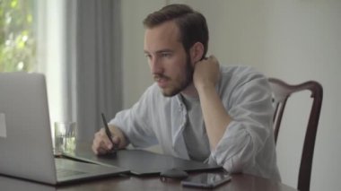 Kendine güvenen sakallı adam bir dizüstü bilgisayar içine bakarak grafik tablet kullanarak çizer. Erkek el çizim 3d animasyon üretim modelleme tasarım modern coworking stüdyo. Gerçek insanlar serisi.