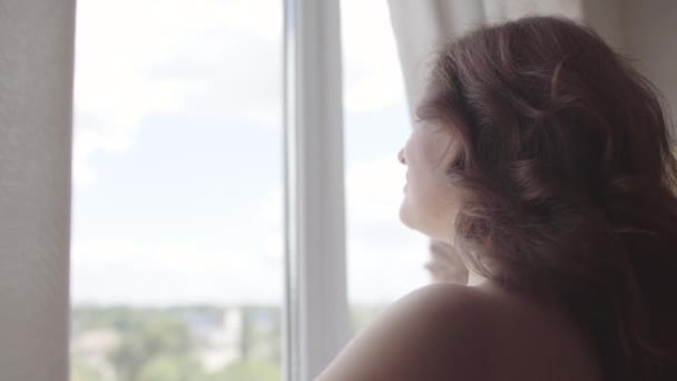 Повзрослевшая женщина, открывающая шторы кружева, стоит в роскошном доме или современном отеле, глядя в окно, наслаждаясь благополучием. Счастливая кавказка встречает новый день . — стоковое видео