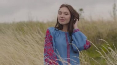 Uzun yaz moda elbisesi giyen güzel kaygısız kız, sahada tribünlerin keyfini çıkararak kameraya güvenle bakıyor. Boş zaman ve güzel bir genç kadın hafta sonu açık havada. Gerçek insanlar serisi.