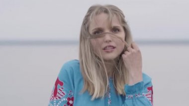 Saçlarına dokunan nakış ile güzel mavi uzun yaz elbisesi çekici genç sarışın kız. Moda kavramı, doğa ile bağlantı, kırsal yaşam