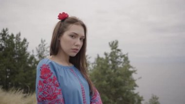 Uzun yaz moda elbisesi giyen güzel bağımsız kız, gölün arka planında yer alan tribünlerin keyfini çıkararak kameraya güvenle bakıyor. Dışarıda genç ve güzel bir kadının boş vakti. Gerçek insanlar serisi.