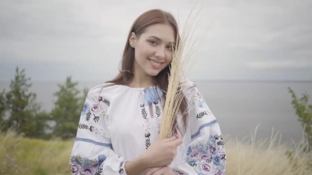 Retrato de la hermosa joven caucásica sosteniendo hierba amarilla en el campo. Concepto de moda, conexión con la naturaleza, estilo de vida rural — Vídeos de Stock