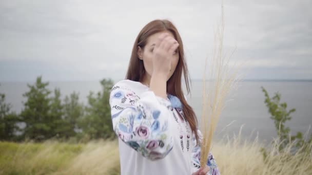 Portret zelfverzekerd zorgeloos Kaukasische meisje dragen lange zomer mode jurk genieten van kijken naar de camera en dan weglopen. Vrije tijd van mooie vrouw die een bos gras buiten houdt. Slow Motion. — Stockvideo