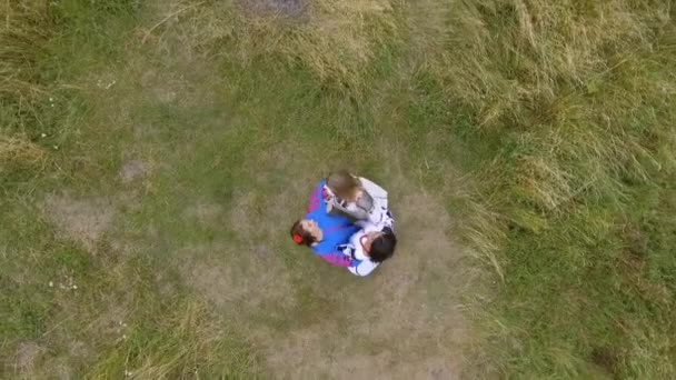 Flygbild på tre flickvänner bär lång sommar mode klänning på fältet. Två kaukasiska och en afroamerikanska flickor spenderar fritid utomhus. Drone skytte. — Stockvideo