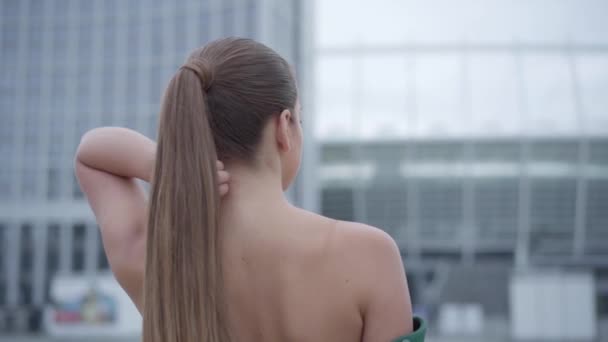 Porträtt av vackra vacker flicka i en fantastisk aftonklänning stående fascinerande på Empty City Square nära skyskrapa. Slow motion — Stockvideo