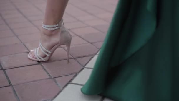 Mujer hermosa elegante no reconocida en vestido de noche esmeralda caminando por la ciudad vacía de la mañana en zapatos de tacón alto . — Vídeos de Stock