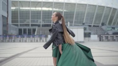 Çarpıcı bir akşam yeşili elbise güzel sevimli kız neşeli ve mutlu yürüyüş ve eğlenceli arama.