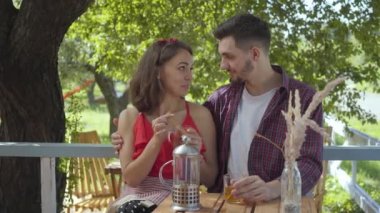 Genç mutlu çift küçük bir masada açık havada oturup konuşuyor ve çay içiyor. Kız arkadaşına sarılan adam. Pozitif erkek ve kadın arka bahçede rahatlatıcı. Evde boş zaman