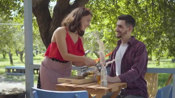 Serveuse professionnelle en chemisier rouge et jupe versant du thé chaud à sa cliente assise à la table en souriant et en flirtant. Café de style vintage — Video