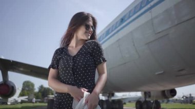 Portre büyük uçağın önünde beyaz şal ve güneş gözlüğü ile güzel esmer kız ve kamera bakarak. Yaz. Seyahat insebunu. Seyahat kavramı, uçak, hafta sonu.