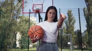 Çekici esmer kadın bir basketbol topu ile kamera parmağını işaret izleyici zorlu. Spor kavramı, güç, rekabet, aktif yaşam tarzı. Spor ve rekreasyon.