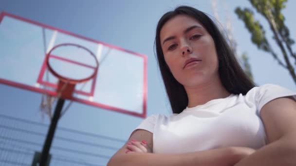 Porträtt tonåring Brunett flicka tittar på kameran stående på basketplan utomhus. Begreppet idrott, makt, konkurrens, aktiv livsstil. Sport och fritid. — Stockvideo