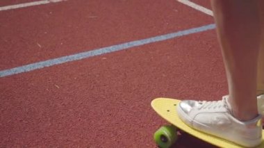 Beyaz spor ayakkabıkız bir açık basketbol sahasında sarı kaykay sürme Closeup kadın bacaklar. Spor kavramı, rekabet, aktif yaşam tarzı. Spor ve rekreasyon.