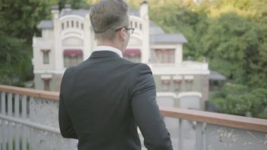 Terasta yürüyen genç başarılı işadamının arka dansı. Ofis yöneticisi doğaya hayran açık havada dinlendirici. Mola süresi, konforlu işyeri