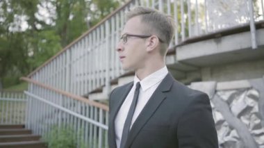 Parkta duran genç ve iyi giyimli işadamının portresi. Ofis müdürü dışarıda müşteriyi bekliyor. Ofis yaşam tarzı, iş konsepti