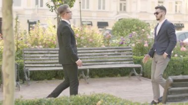 İki genç ortak parkta buluşup el sıkışıyor. Kendine güvenen yönetici, müşterisi ile dışarıda buluşuyor. İş toplantısı, iş ilişkisi.