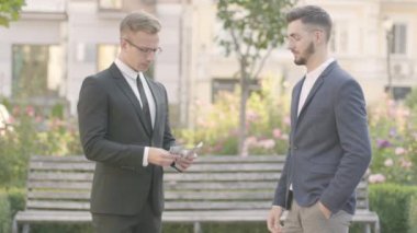 İki genç iyi giyimli ortak parkta buluştu. Kendine güvenen bir yönetici parayı sayıyor ve dışarıda adama veriyor. İş toplantısı, iş ilişkisi. Nakit ödeme