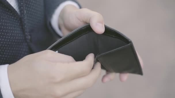 Joven hombre de negocios en un traje oficial mirando en su cartera vacía después del trato y poniéndolo en su bolsillo. Primer plano . — Vídeos de Stock