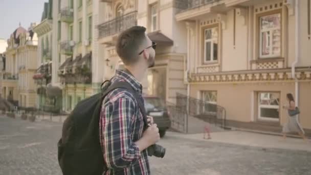 Boldog csípő turista alkalmi felszerelés fényképezés épületek régi utcán a modern kamera szakmai objektívvel — Stock videók