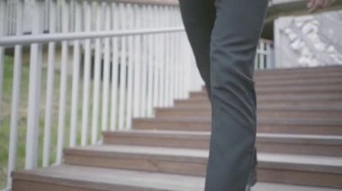 Pahalı takım elbise ve ayakkabı alt katta yürüyen şık bir iyi giyimli işadamı bacakları. Ofis yaşam tarzı, iş konsepti. Takım elbiseli adam dışarıda yürüyor. Yavaş çekim